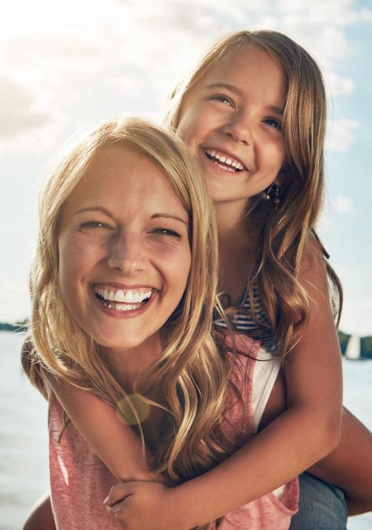 woman smiling with her daughter on her back