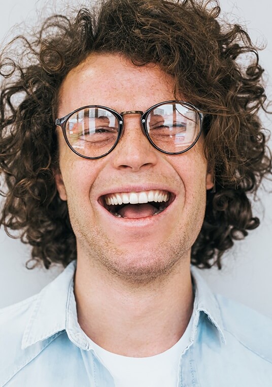 man with curly hair and glasses smiling